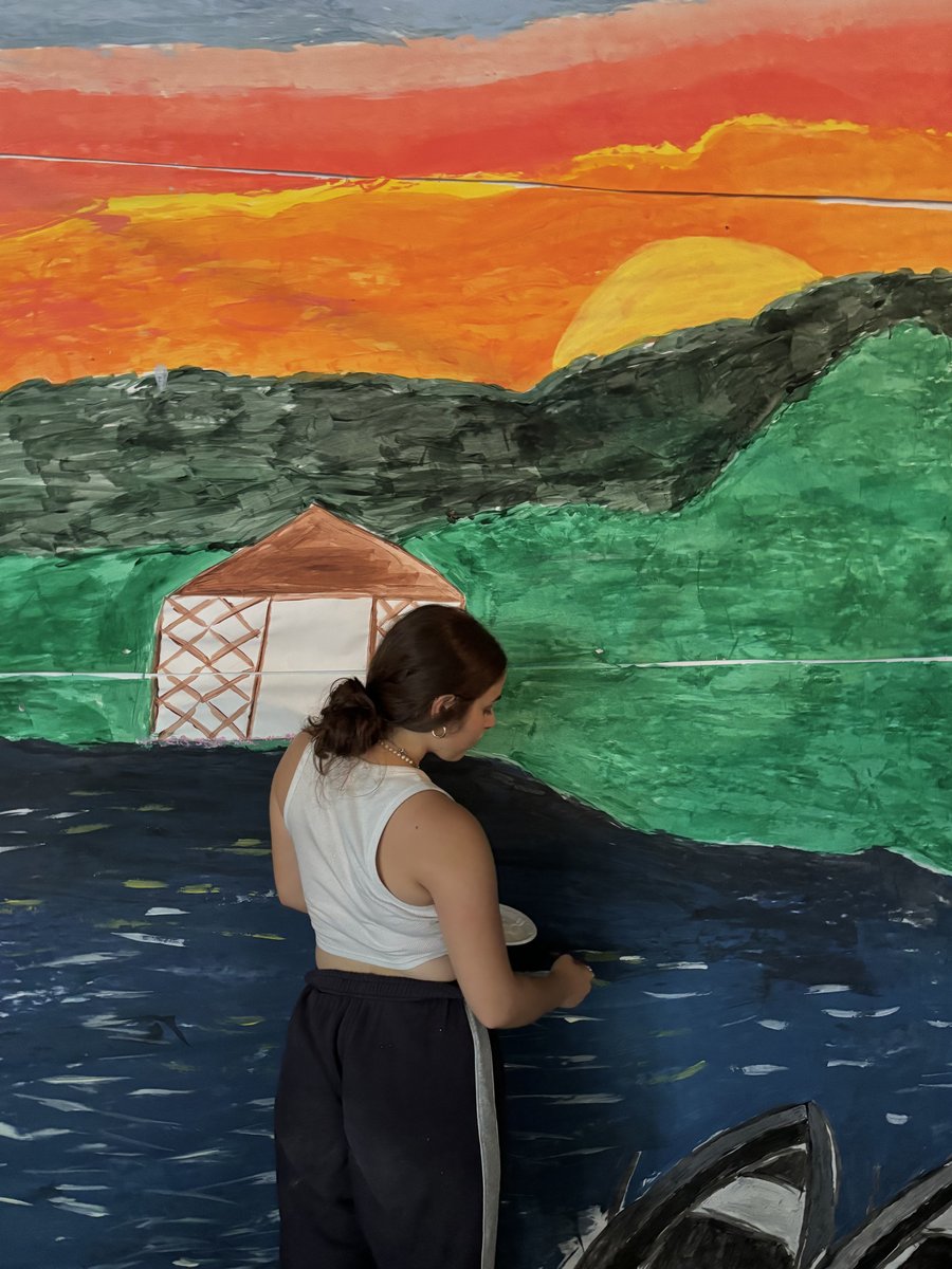 Shoshi painting a large sunset mural in the studio